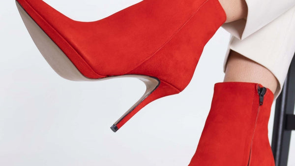 Woman modelling fashionable red high-heeled suede ankle boots