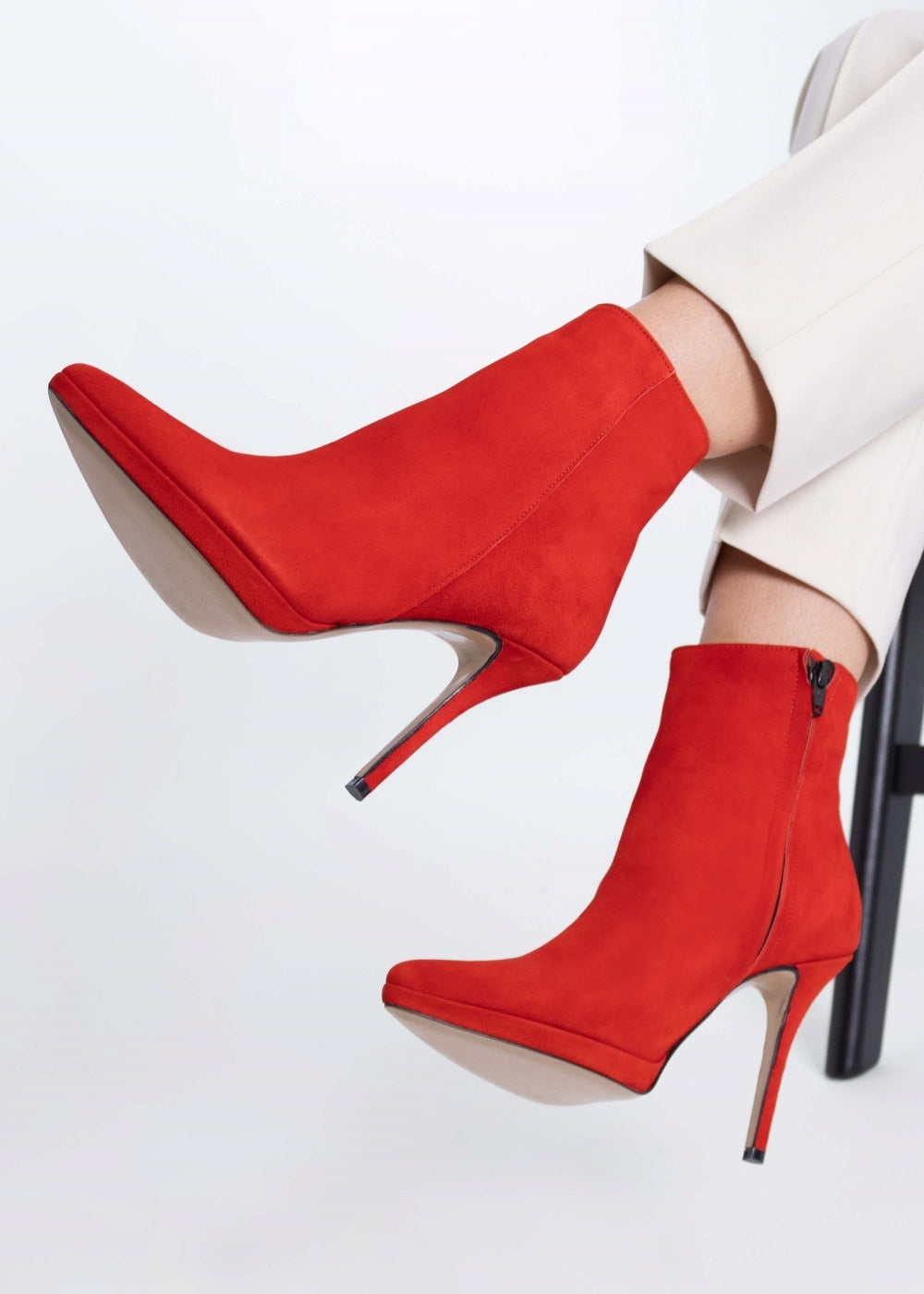 Woman modelling fashionable red high-heeled suede ankle boots